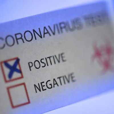 Label with a red box with a cross in it, indicating a positive COVID test result 